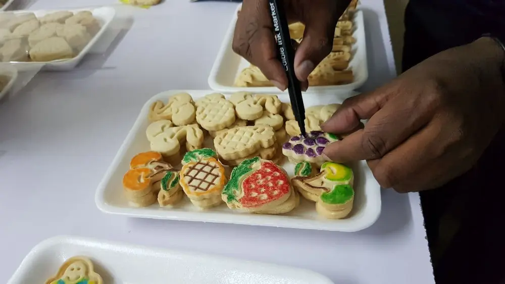  a man coloring cookies with edible marker